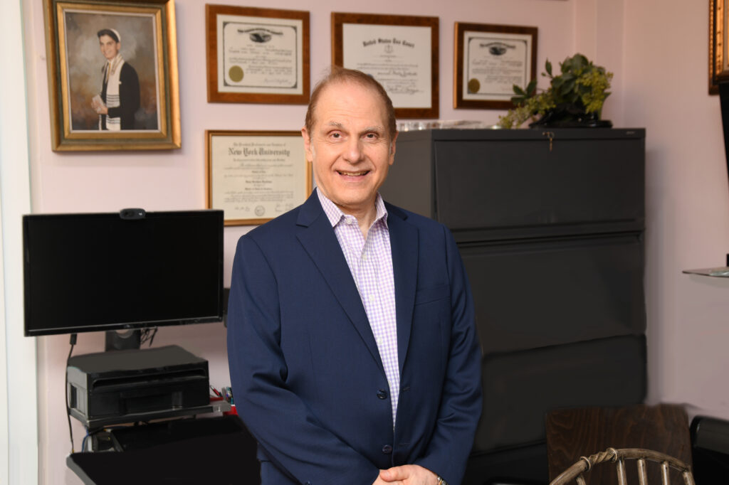 Samuel Kaufman smiling in his office in front of his awards